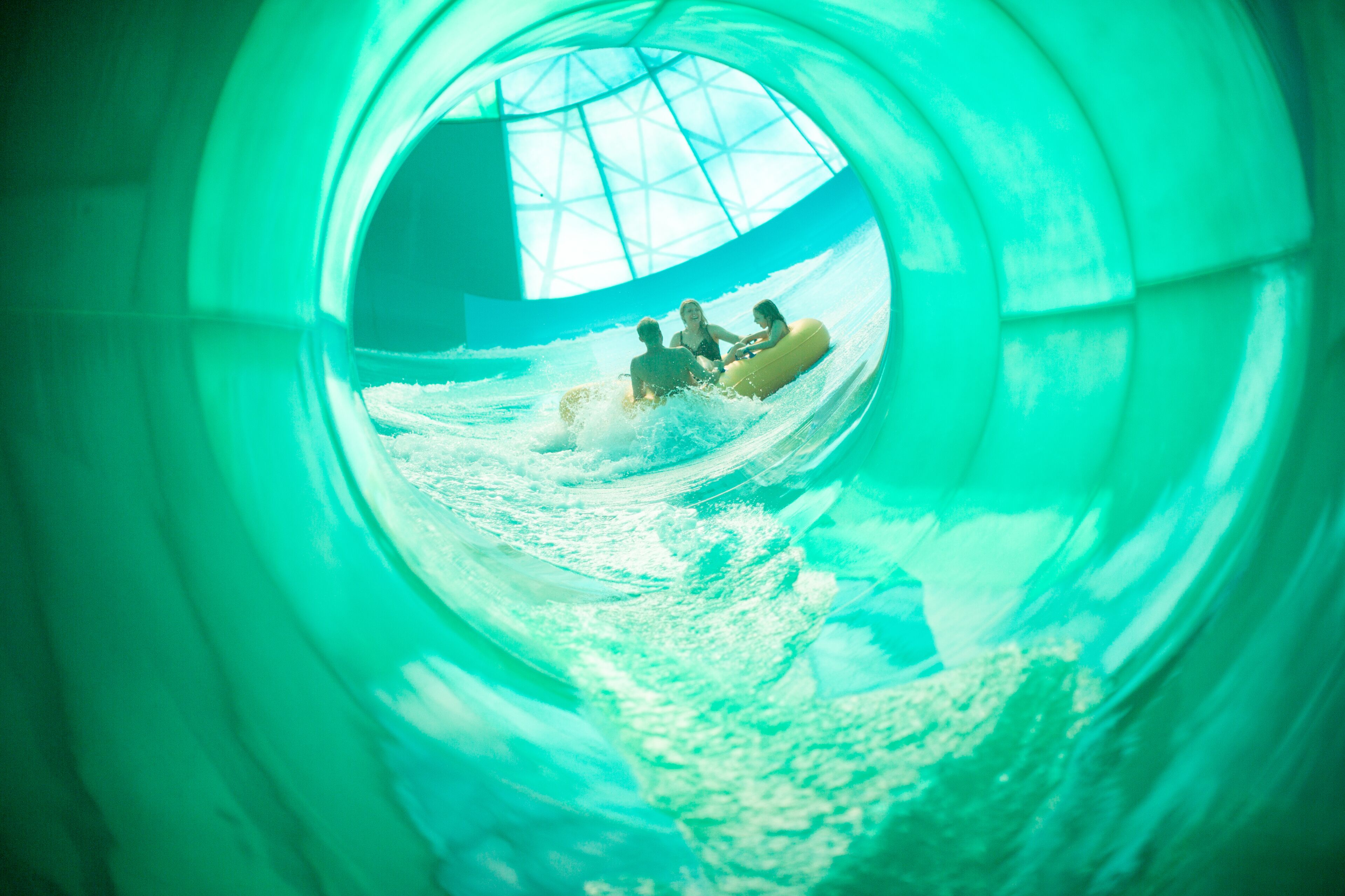 Un tobogán de agua con un túnel transparente y una estructura tipo cúpula al fondo.