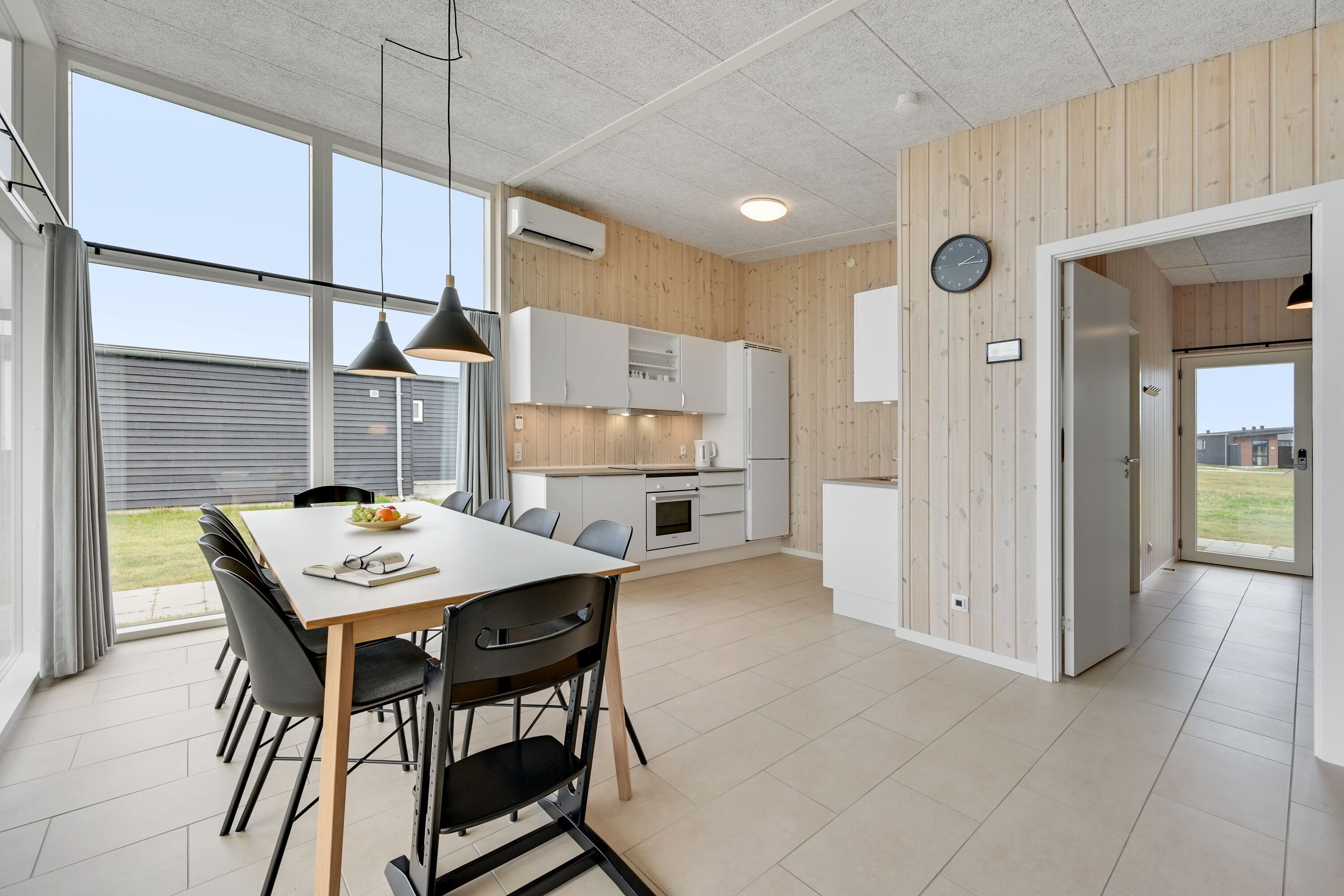 Una cocina moderna con armarios blancos, una mesa de comedor con sillas y vistas al exterior.