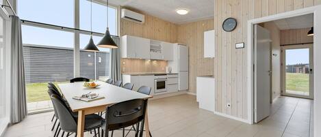 Una cocina moderna con armarios blancos, una mesa de comedor con sillas y vistas al exterior.