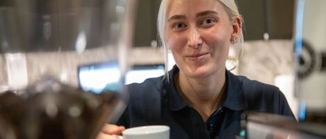 Una persona sosteniendo una taza en una cocina moderna con electrodomésticos de acero inoxidable.