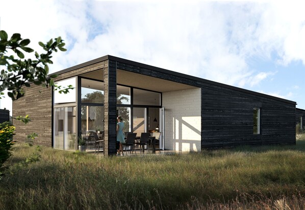 A modern house with large glass doors, a wooden exterior, and a grassy yard.