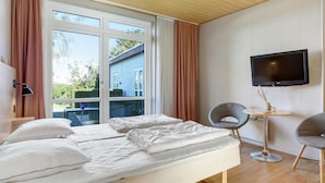 A modern hotel room with a large bed, a TV mounted on the wall, and a view of the outside. - Stunning apartment in Allinge with WiFi (Allinge)