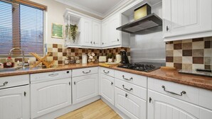 Una cocina moderna con gabinetes blancos, extractor de acero inoxidable y salpicadero a cuadros.