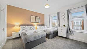 Un dormitorio moderno con cama, mesitas de noche, una lámpara y un ventanal con cortinas.