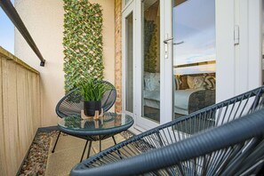 A glass table with chairs, a potted plant, and a sliding glass door leading to a patio area.