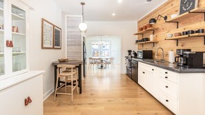 Una cocina moderna con armarios de madera, un comedor con una mesa redonda y sillas, y vista al salón.