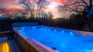 Un jacuzzi con cubierta de madera y vistas al atardecer.