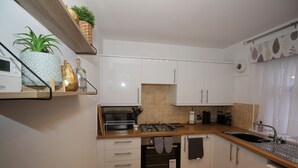 A modern kitchen with white cabinets, a wooden countertop, a built-in oven, and a sink. - Historic Old Town 2 Bed Ground Floor Apartment (Stirling)