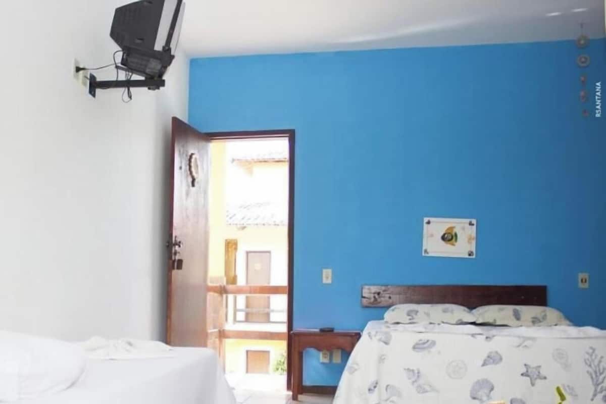 A bedroom with a bed, a nightstand, a wall-mounted lamp, and a door leading to an outdoor area.
