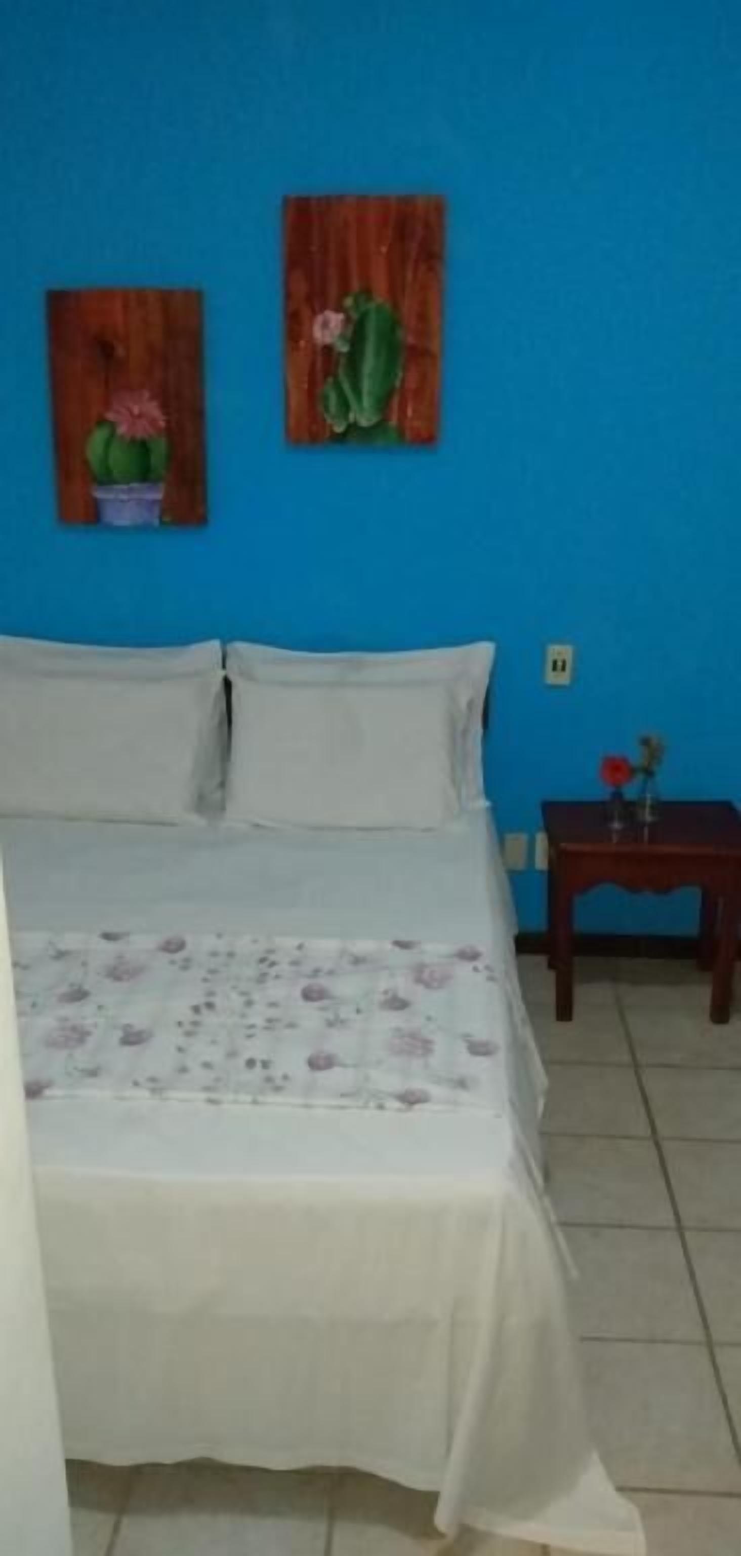 Ein Schlafzimmer mit einem Bett, einem Nachttisch und zwei an der Wand hängenden Bildern.
