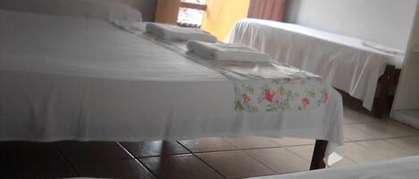 Ein Hotelzimmer mit einem großen Bett, einem kleineren Bett und einer Bank.