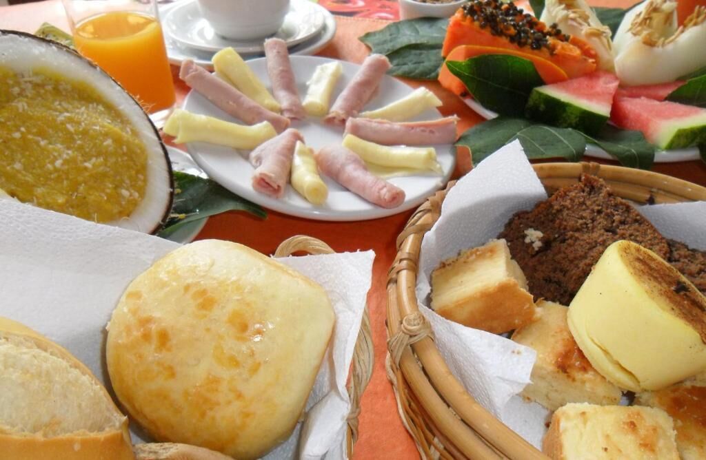 A breakfast spread with various foods including bread, cheese, ham, and fruits.