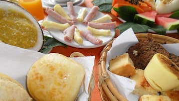 Un assortiment de produits pour le petit-déjeuner comprenant du pain, du fromage, du jambon et des fruits.