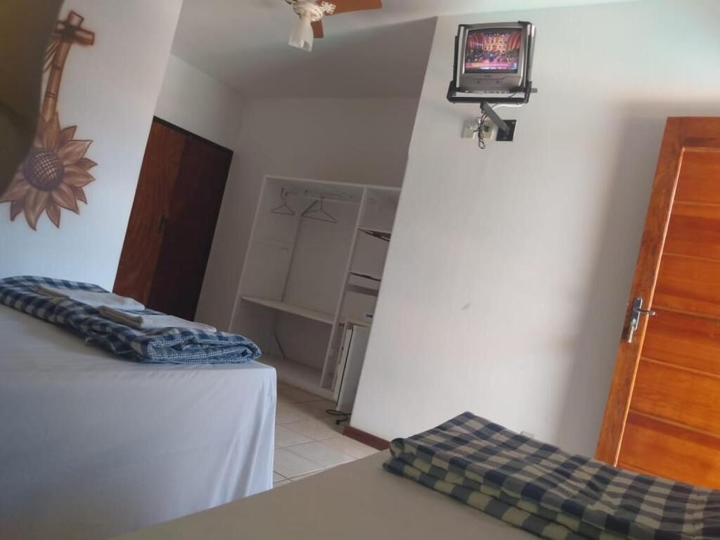 Une chambre à coucher comprenant un lit, une armoire, un téléviseur fixé au mur et un ventilateur de plafond.