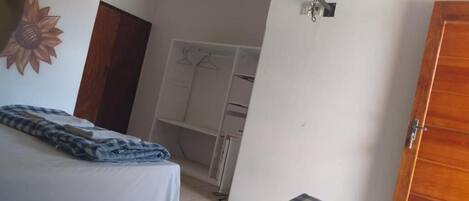 A bedroom with a bed, a wardrobe, a television mounted on the wall, and a ceiling fan.