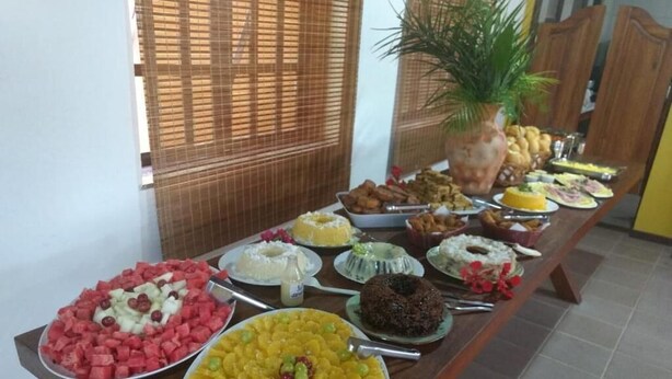 Una mesa de buffet con diversos platos, entre ellos frutas, tartas y pasteles.