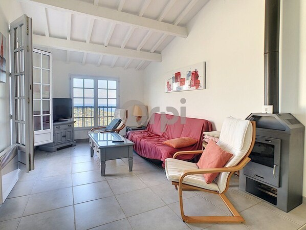 A spacious living room with a high ceiling, a fireplace, a sofa, a TV, and a dining area. - Two-bedroom villa on a property with a pool and tennis court, ocean views, and a clubhouse (SAINTE MAXIME)