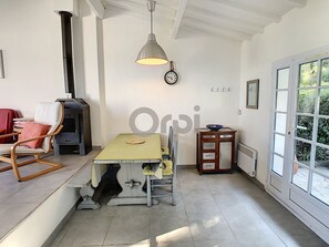 Een eetgedeelte met een tafel, stoelen, een klok, een verwarming en een raam met uitzicht.