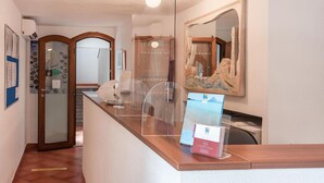 Una zona de recepción con mostrador de madera, una vitrina de vidrio y un cuadro colgado en la pared.