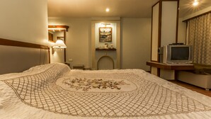 Una habitación de hotel con una cama grande, televisión y chimenea.