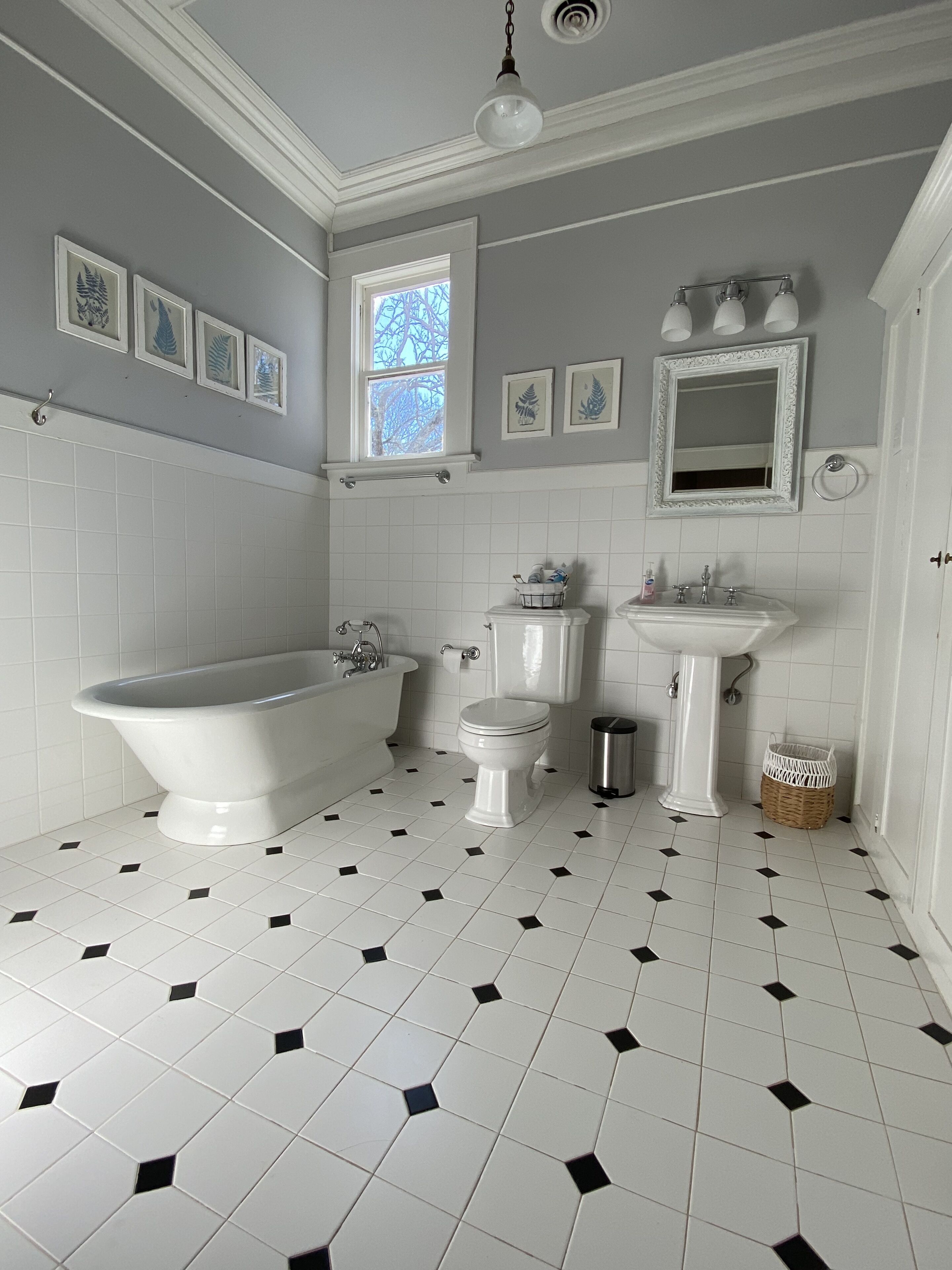 Badeværelse med badekar, toilet, håndvask og et vindue.
