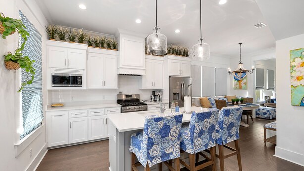 A modern kitchen with white cabinetry, a central island with bar stools, and pendant lighting. - Gorgeous 4 bed/3.5 bath Home with Private Pool (St. Simons Island)
