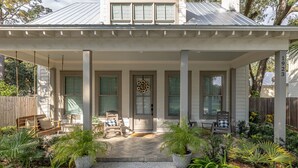 A covered porch with a swing, a door with a wreath, and potted plants. - Gorgeous 4 bed/3.5 bath Home with Private Pool (St. Simons Island)