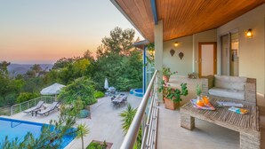 A balcony with a pool, outdoor furniture, and a view of the surrounding landscape.