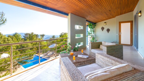 A modern outdoor seating area with a pool, wooden ceiling, and a view of the mountains.