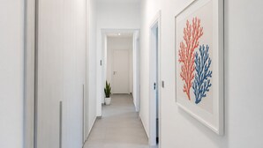 En hall med vita väggar, en krukväxt och ett inramat konstverk.