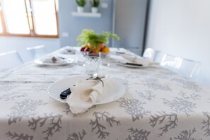 A dining table set with plates, glasses, and a centerpiece of flowers.