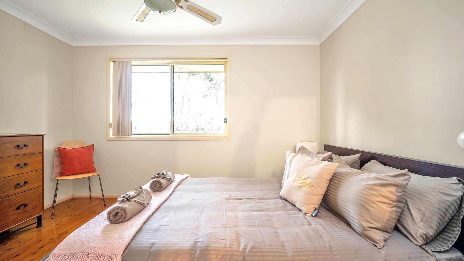 A bedroom with a bed, a dresser, a chair, and a window.