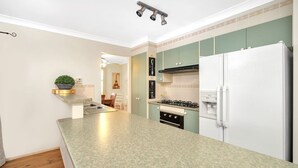 A kitchen with a granite countertop, a white refrigerator, a stove, and a sink. - WaterSide by Experience Jervis Bay (Sanctuary Point)