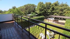 Ein Balkon mit Blick auf einen Parkplatz, eine grüne Wiese und Bäume.