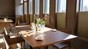 A dining area with tables and chairs, a vase with flowers, and a window with blinds. - Wyndham Fengqing Resort (Lincang)