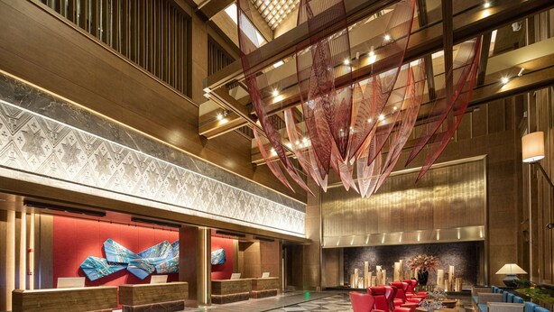 A spacious lobby with a reception desk, seating area, and a large abstract art piece. - Wyndham Fengqing Resort (Lincang)