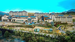 A hotel with multiple buildings, a landscaped garden, and a body of water. - Wyndham Fengqing Resort (Lincang)
