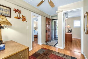 Un couloir doté d’un plancher en bois, d’un tapis à motifs, d’une porte ornée de panneaux décoratifs et d’un ventilateur de plafond.