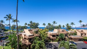 Een resort met meerlaags gebouwen, palmbomen en uitzicht op de oceaan.
