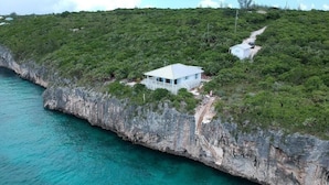 Een huis op een klif met uitzicht op turquoise water.