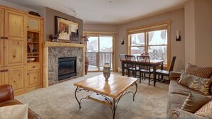 A living room with a fireplace, wooden cabinets, a dining table, and a sofa. - Copper Springs Condo with Panoramic Mountain Views - CS331 by Redawning (Copper Mountain)