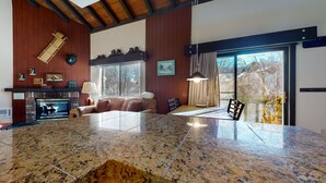 Un amplio salón con encimera de granito, chimenea, sofá y mesa de comedor.