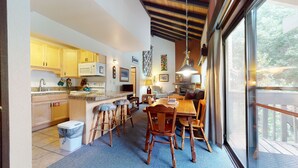 Una cocina amplia con armarios de madera, un comedor con mesa y sillas de madera, y un ventanal con vistas al exterior.