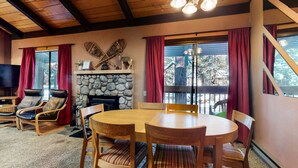 A cozy room with a stone fireplace, a wooden dining table, and leather chairs. - Horizons 4 186 Centrally Located, Spacious Mammoth Home with Cozy Fireplace by RedAwning (Mammoth Lakes)