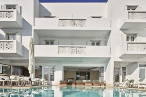 A modern hotel with a pool, outdoor seating, and balconies with decorative patterns.