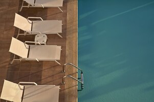 An aerial view of a poolside area with sun loungers and a pool.