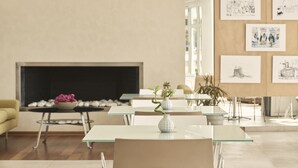 A modern interior with a fireplace, glass tables, and artwork on the walls. - Oxygen Favie by GHH (Tinos)