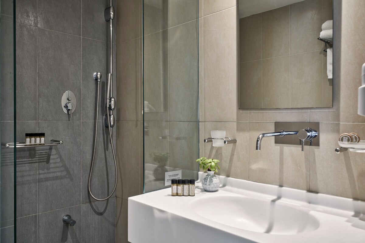 A modern bathroom with a glass-enclosed shower, a white sink, and a mirror above it.