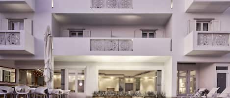 A modern hotel with a pool area, multiple balconies, and a well-lit interior.
