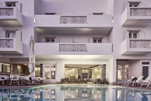 A modern hotel with a pool area, multiple balconies, and a well-lit interior.